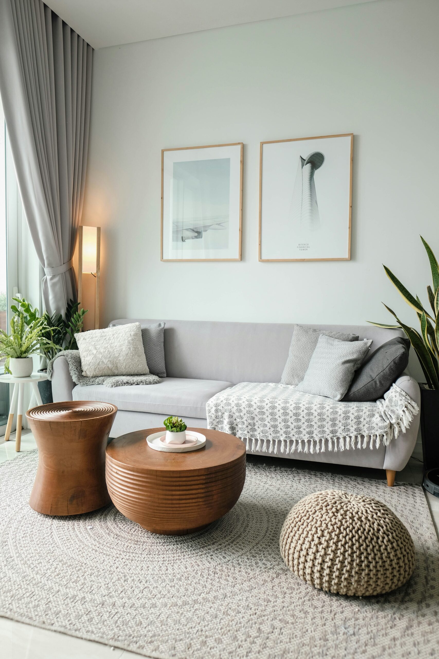 A tidy living area with a white rug, brown tables, and a white sofa.